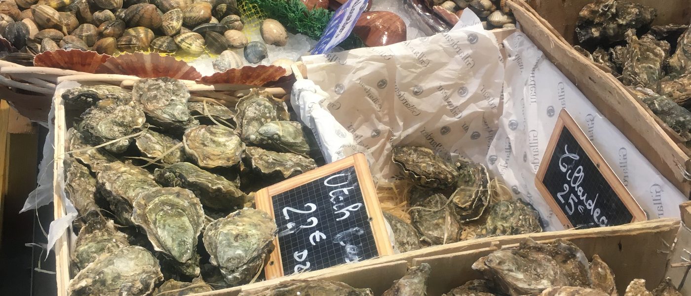Fischmarkt in Frankreich mit Austernkisten und Meeresfrüchten